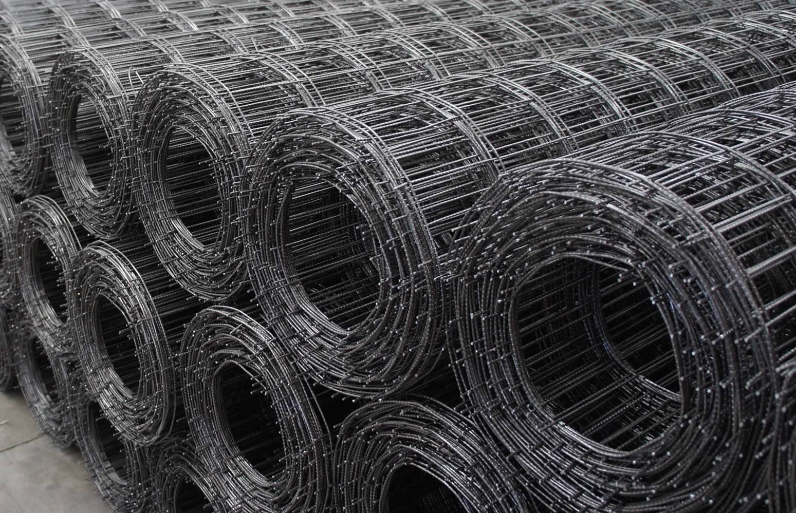 Three layers of black color welded concrete mesh rolls on the ground.